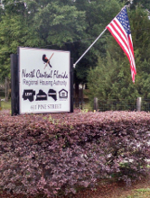 North Central Florida Regional Housing Authority sign with American flag surronded by flowers.